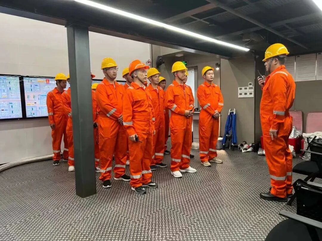 身穿橙色工作服的学员接受安全讲解